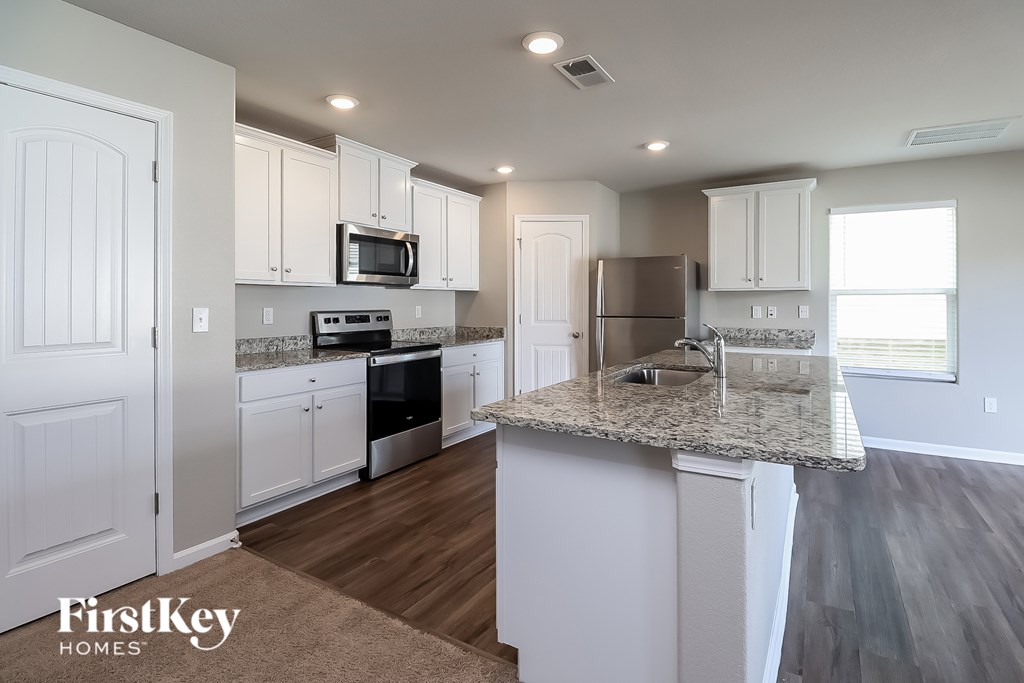 A kitchen with a granite countertop and white cabinets.