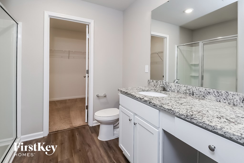 A bathroom with a marble countertop and white cabinets.