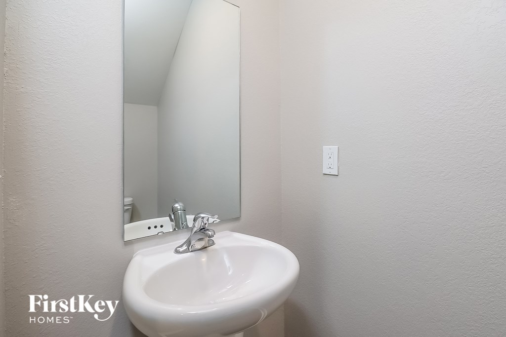 A white sink in a bathroom with a mirror above it.
