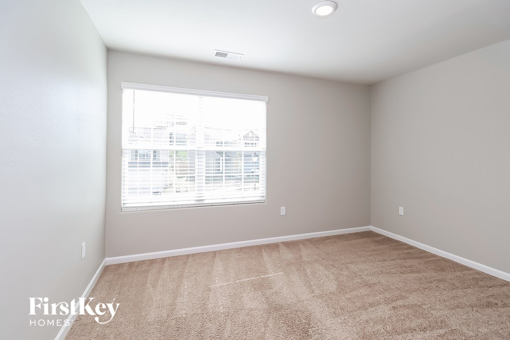 A room with a carpeted floor and a window with blinds.