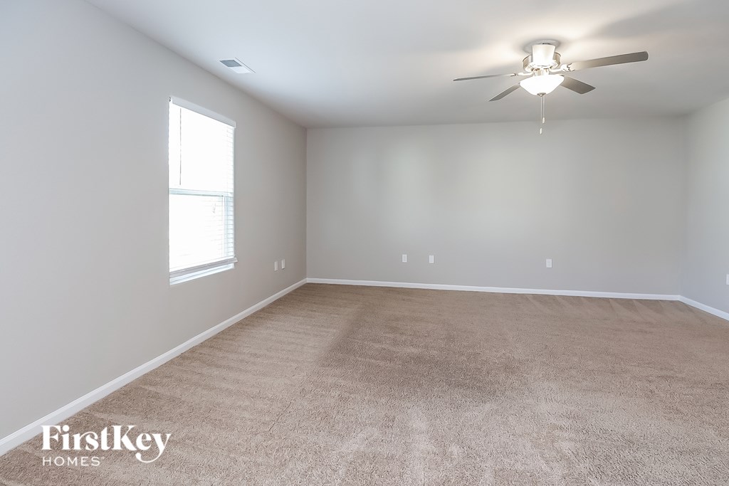 A spacious room with a carpeted floor and a ceiling fan.
