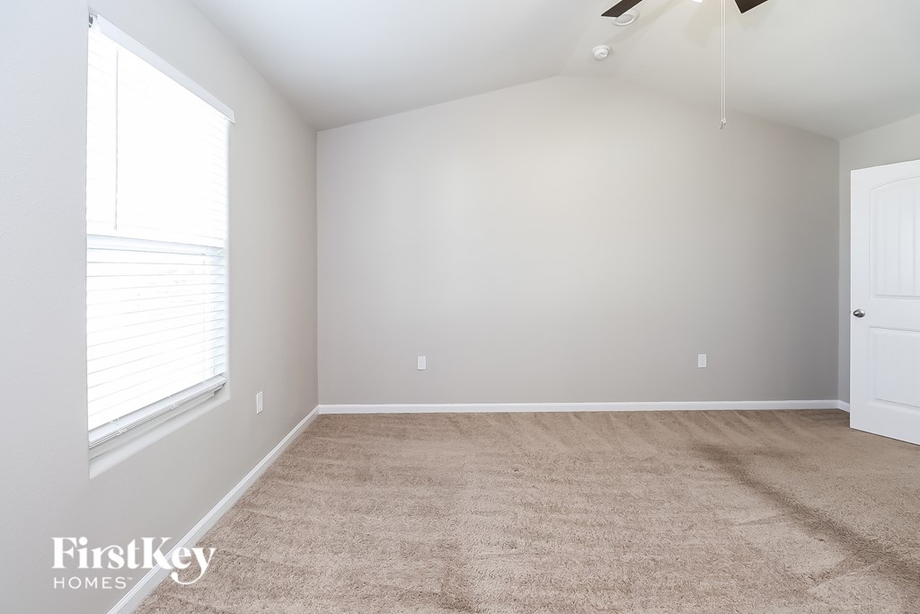 A room with a carpeted floor and a ceiling fan.