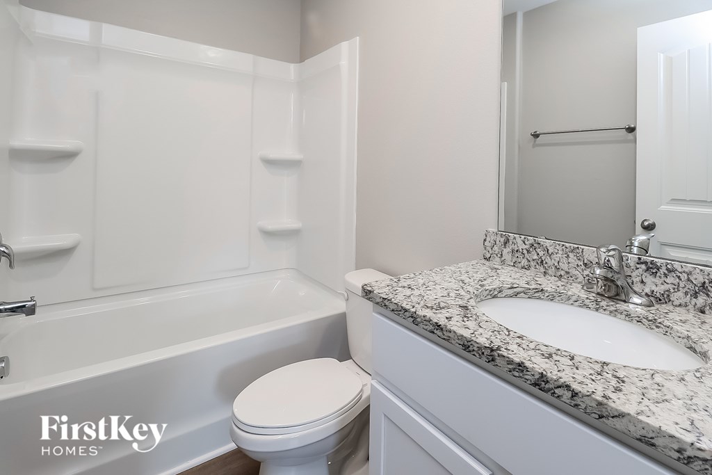 A white bathroom with a marble countertop and a white toilet.