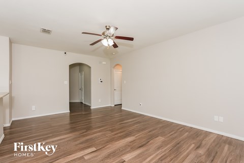 A spacious room with a ceiling fan and wooden flooring.