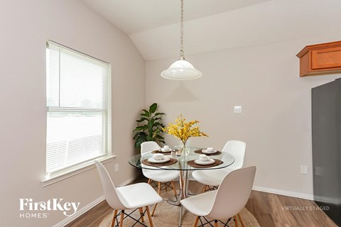 A dining room with a glass table and white chairs.