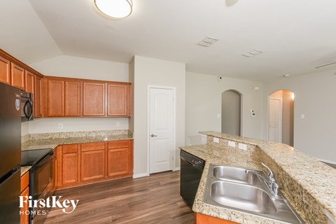 A kitchen with wooden cabinets and a black fridge.