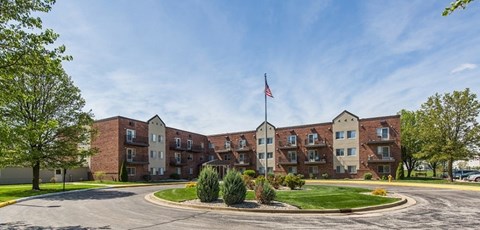 A large brick building with a flag on top and a roundabout in front.