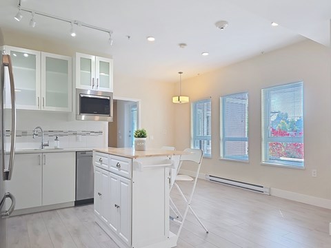 A kitchen with white cabinets and a white chair.