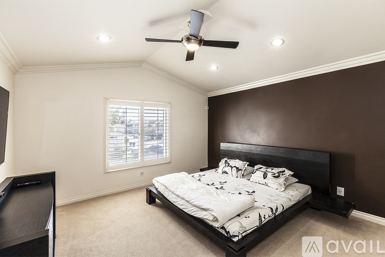 A bedroom with a large bed and a ceiling fan.