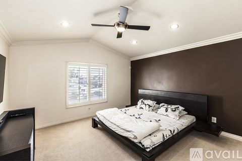 A bedroom with a large bed and a ceiling fan.