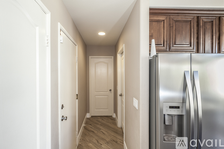 A kitchen with a refrigerator and wooden cabinets.