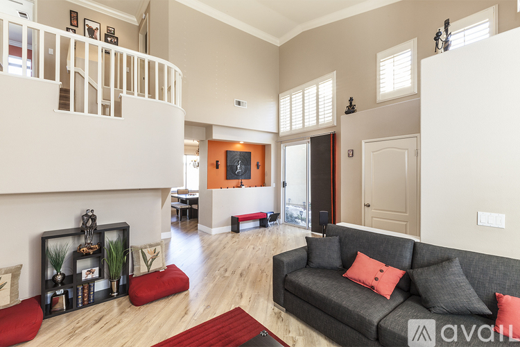 A living room with a grey couch and a red rug.