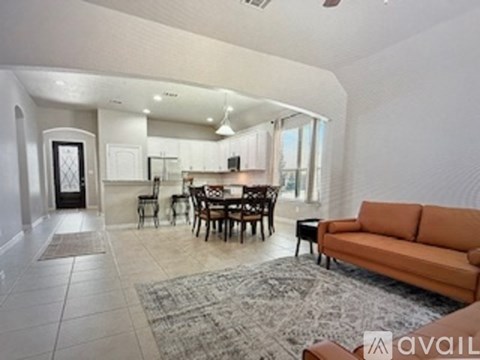 A living room with a brown couch and a dining table with chairs.