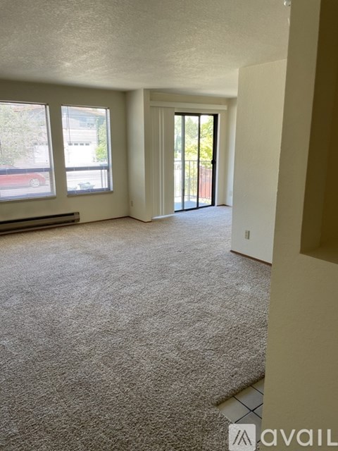A carpeted room with a door leading to a balcony.