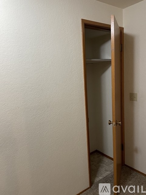 A white wall with a wooden door and a shelf.