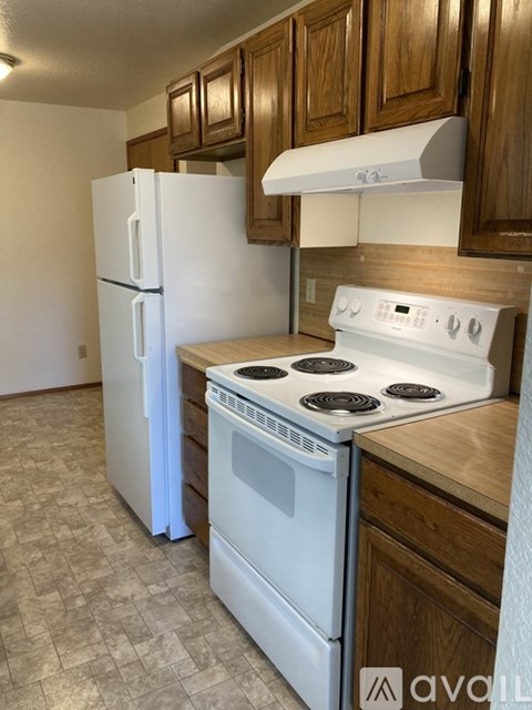 A white stove and refrigerator in a kitchen with wooden cabinets.