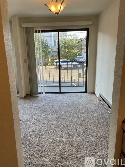 A hallway with a carpeted floor and a sliding glass door leading to a parking lot.