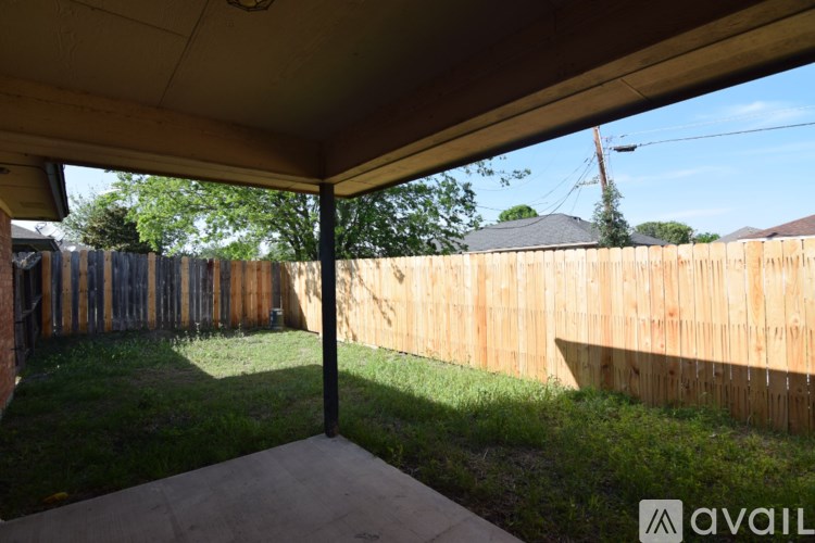 A patio with a wooden fence and a grassy area.
