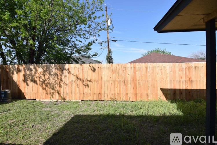 A backyard with a wooden fence and a tree.