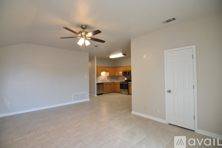 A spacious room with a ceiling fan and a door leading to another room.