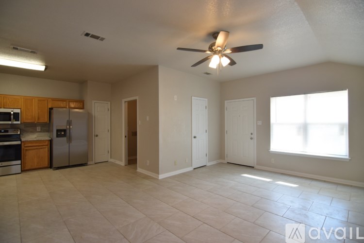 A spacious living room with a ceiling fan and tiled flooring.