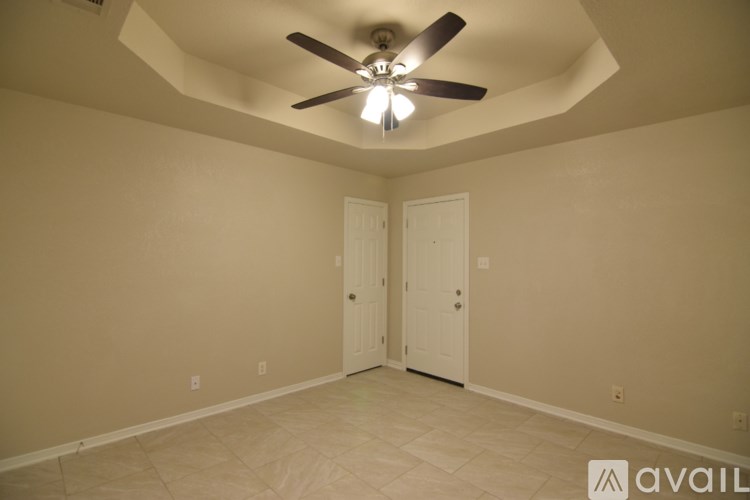 A room with a ceiling fan and two doors.