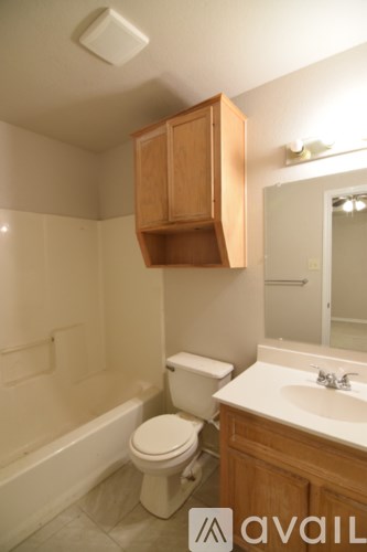 A bathroom with a toilet, sink and wooden cabinet.