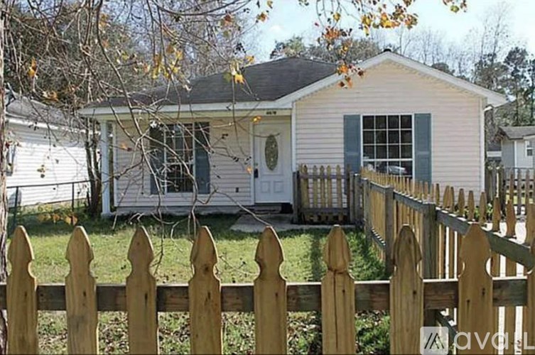 A small house with a wooden fence in front.
