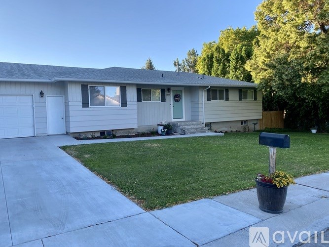 A house with a driveway and a mailbox with flowers in front.