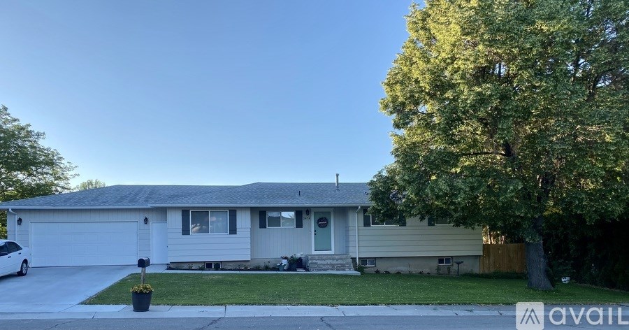 A house with a car parked in front and a tree to the right.