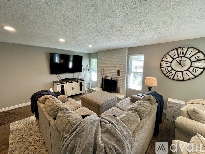 A living room with a large clock on the wall and a couch with a blanket on it.