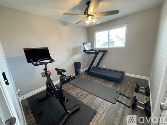 A room with a treadmill, exercise bike, and weights.