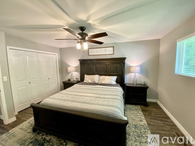 A bedroom with a bed, nightstands, and a ceiling fan.