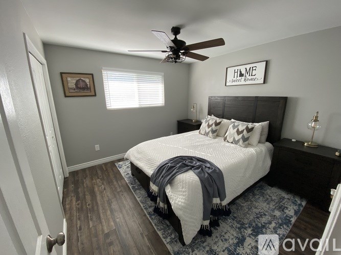 A bedroom with a bed, a ceiling fan, and a picture on the wall.