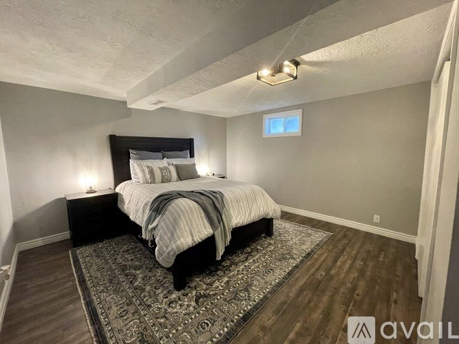 A bedroom with a bed, nightstand, and rug.