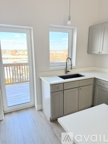 A kitchen with white cabinets and a large window overlooking a balcony.