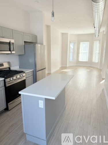 A kitchen with a white island and stainless steel appliances.