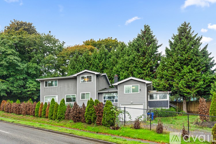 A house with a grey roof and a fence in front of it.