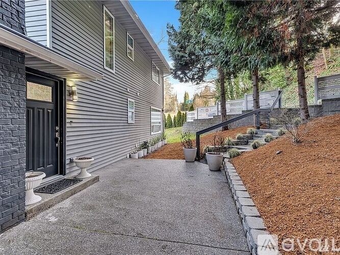 A house with a grey siding and a black door is shown.