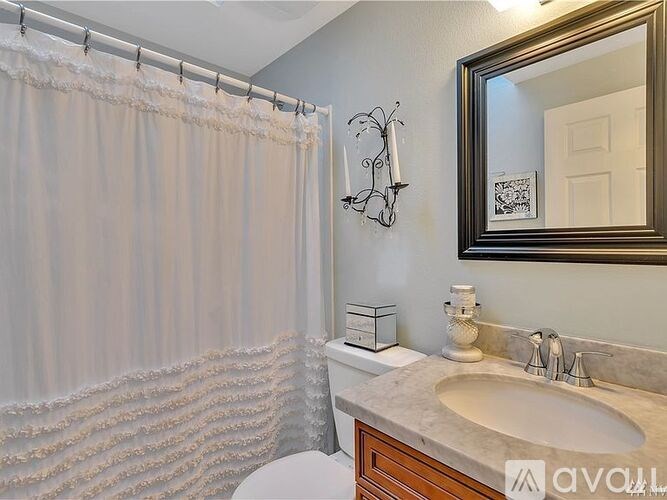 A bathroom with a white toilet, a sink, a mirror, and a shower curtain.