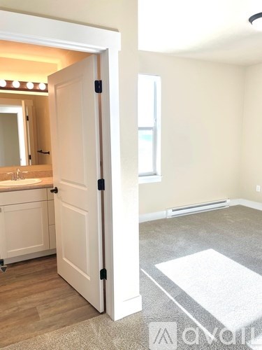 A white door is open to a bathroom with a sink and mirror.