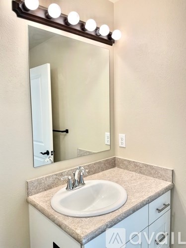 A bathroom sink under a mirror with lights on it.