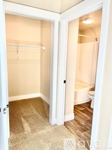 A white door is open to a bathroom with a toilet and a bathtub.