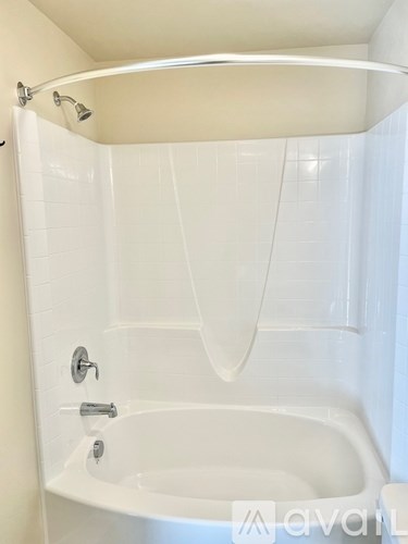 A white bathtub with a shower head and faucet.