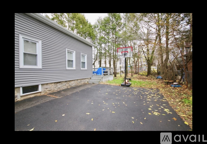 A basketball hoop is in the backyard of a house with a grey siding.