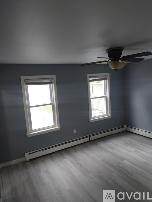 A room with a ceiling fan and two windows.