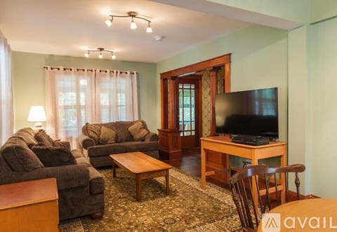A living room with a couch, chair, and television.