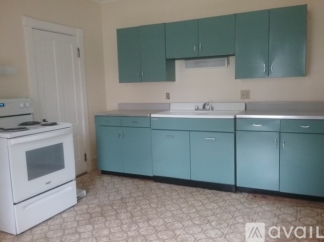 A kitchen with white appliances and teal cabinets.