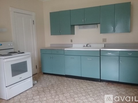 A kitchen with white appliances and teal cabinets.