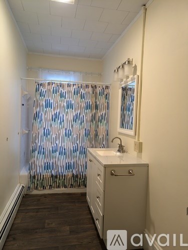A bathroom with a white sink and a shower curtain with blue and white stripes.